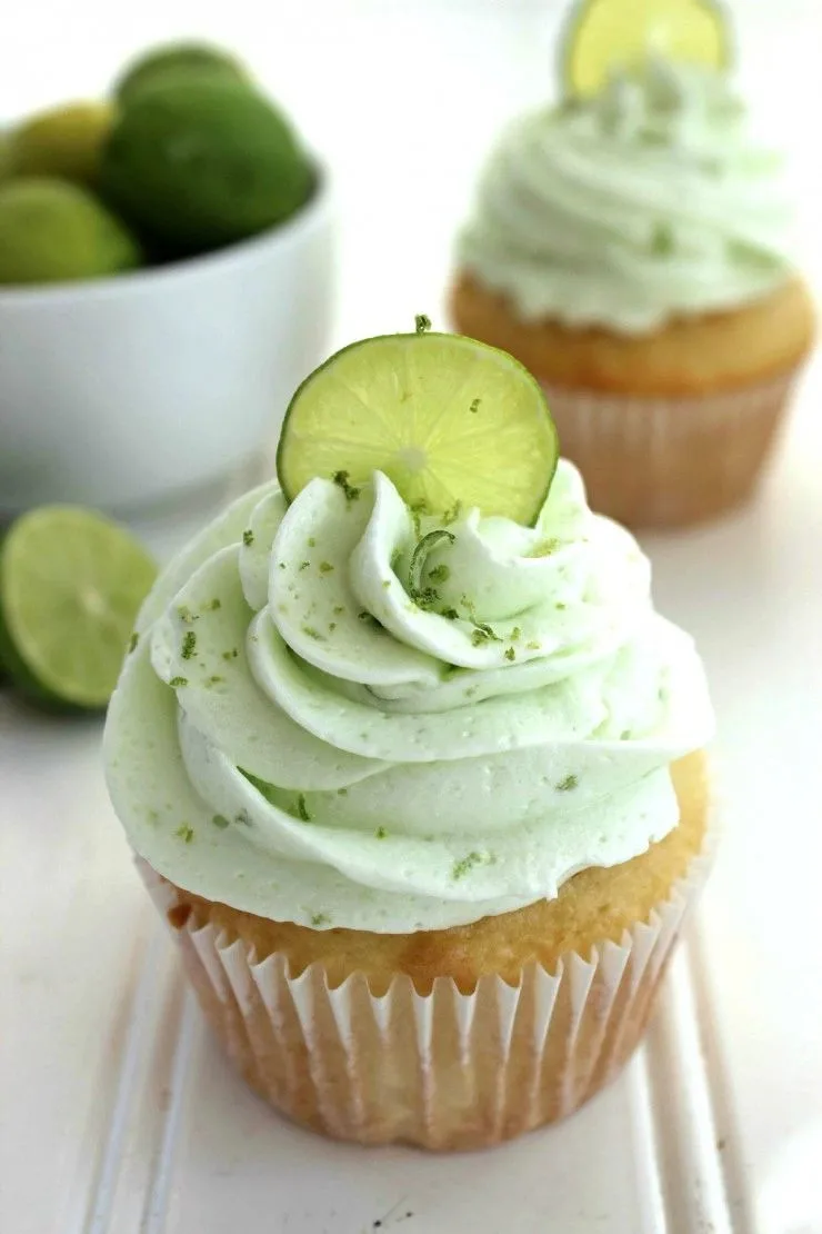 Cupcake topped with swirled green-tinted frosting, lime zest, and a lime slice garnish.